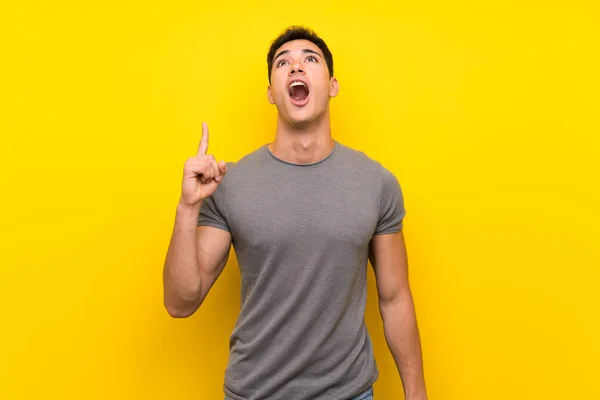 Hombre Guapo Sobre Aislada Pared Amarilla Apuntando Hacia Arriba Sorprendido —  Fotos de Stock