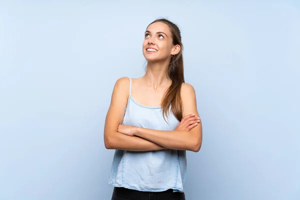 年轻女子在孤独的蓝色背景上抬起头微笑着 — 图库照片