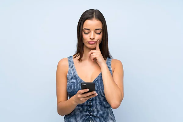 Mujer Joven Sobre Pared Azul Aislada Usando Teléfono Móvil — Foto de Stock