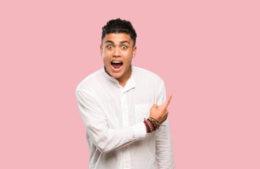 Genç adam şaşırttı ve renkli arka plan üzerinde yan işaret