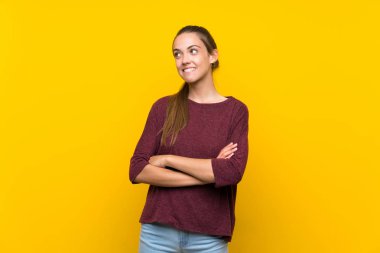 İzole edilmiş sarı arka planda genç bir kadın gülümserken yukarı bakıyor