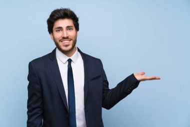 Bir reklam eklemek için avuç üzerinde copyspace hayali tutan izole mavi duvar üzerinde İşadamı