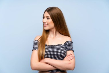 Genç bir kadın mavi arka planda gülüyor.