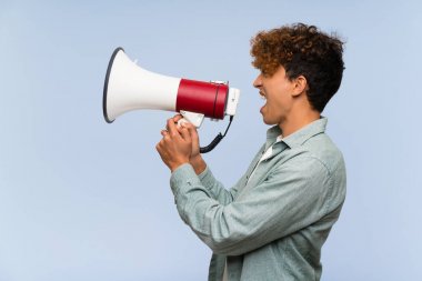 Izole mavi duvar üzerinde genç afro-amerikan adam bir megafon ile bağırıyor