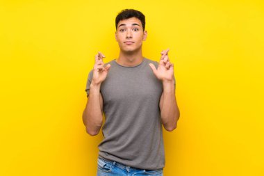Parmakları geçiş ve en iyi dilek ile izole sarı duvar üzerinde Yakışıklı adam