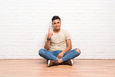 Genç adam yere oturup işaret parmağıyla işaret etmek harika bir fikir.