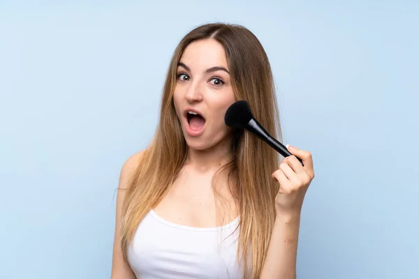 Mujer Joven Sobre Fondo Azul Aislado Con Cepillo Maquillaje —  Fotos de Stock