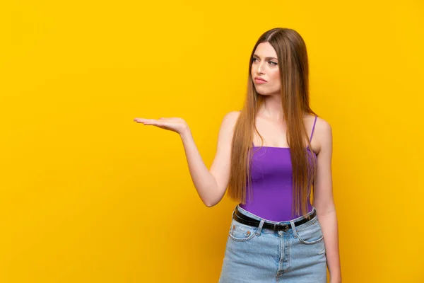 Jovem Mulher Sobre Isolado Amarelo Fundo Segurando Copyspace Com Dúvidas — Fotografia de Stock