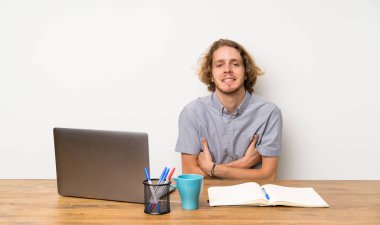 Kollarını ön konumda çapraz tutan bir dizüstü bilgisayar ile Sarışın adam