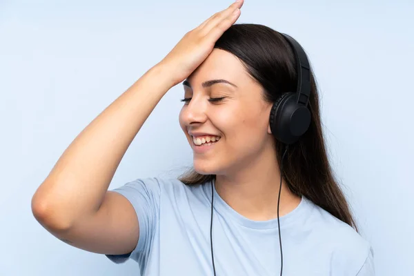 Jovem Mulher Ouvindo Música Sobre Fundo Azul Isolado Percebeu Algo — Fotografia de Stock