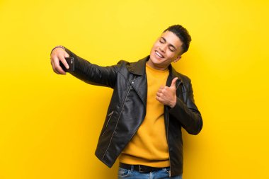 Izole sarı arka plan üzerinde genç adam selfie yapma