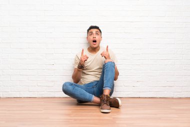 Genç adam yere oturup işaret parmağıyla işaret etmek harika bir fikir.