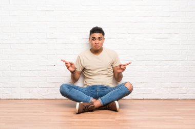 Yerde oturan genç adam yan taraftakileri işaret ediyor. Şüpheleri var.