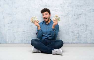Yerde oturan ve çok para alan genç adam.
