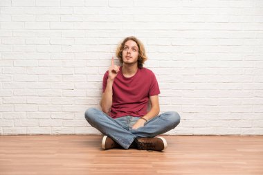 Sarışın adam yerde oturan bir fikir parmağını işaret düşünme