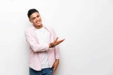 Izole beyaz duvar üzerinde genç adam gelmeye davet için yan ellerini uzatıyor