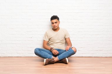 Yerde oturan genç adam kollarını çapraz tutarak