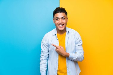 Izole renkli arka plan yan parmak işaret üzerinde genç adam