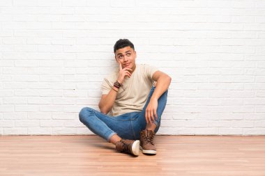 Genç adam yerde oturmuş bir fikir düşünüyor.