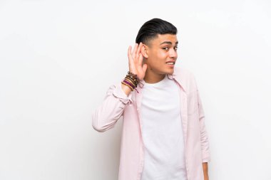 Izole beyaz duvar üzerinde genç adam bir şey dinlerken