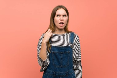 Yorgun ve hasta ifade ile pembe duvar üzerinde tulum ile genç kadın