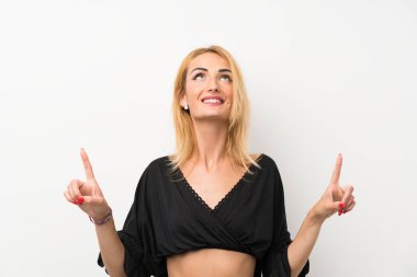 Izole beyaz duvar üzerinde genç sarışın kadın şaşırttı ve işaret