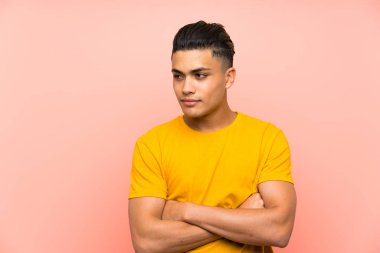 Izole pembe duvar görünümlü yan üzerinde sarı gömlekli genç adam
