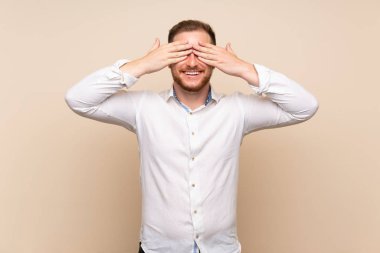 Elleriyle gözleri kaplayan izole arka plan üzerinde Blonde adam