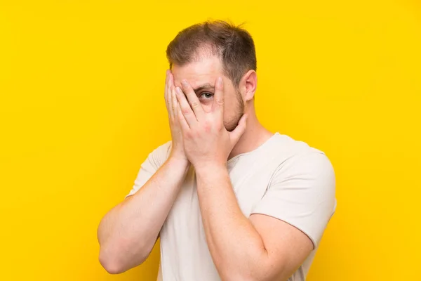Pohledný Muž Přes Žluté Pozadí Zakrývající Oči Procházející Prsty — Stock fotografie
