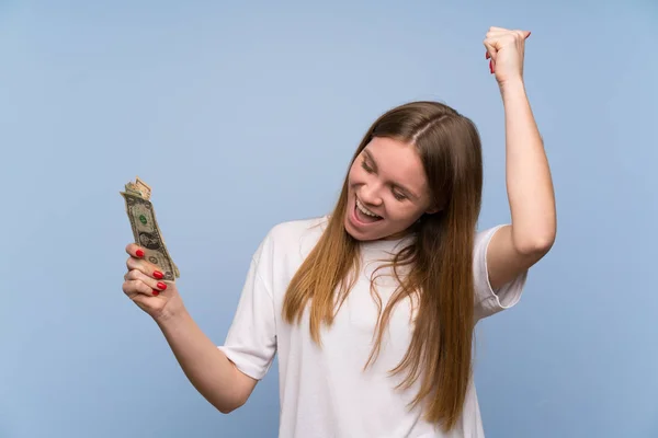 Joven Mujer Sobre Pared Azul Tomando Montón Dinero —  Fotos de Stock