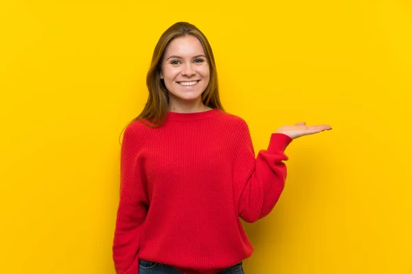 手のひらに架空 Copyspace を保持している黄色の壁に広告を挿入する若い女性 — ストック写真