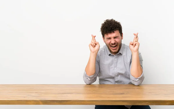 Joven Con Una Mesa Con Los Dedos Cruzados — Foto de Stock