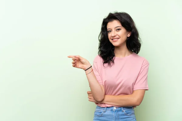 Jovem Mulher Sobre Isolado Fundo Verde Apontando Dedo Para Lado — Fotografia de Stock