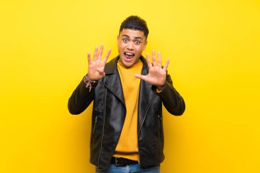 Izole sarı arka plan üzerinde genç adam parmakları ile dokuz sayma