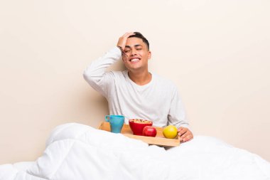 Yatakta gülerek kahvaltı alan genç adam