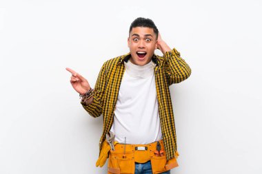 Izole beyaz duvar üzerinde genç elektrikçi adam şaşırttı ve yan parmak işaret