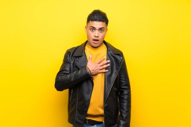 Izole sarı arka plan üzerinde genç adam şaşırttı ve doğru bakarken şok