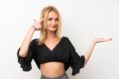 Izole beyaz duvar üzerinde genç sarışın kadın kafasına parmak koyarak delilik jest yapma