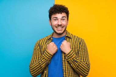 Bir zaferi kutlayan renkli duvar üzerinde kıvırcık saçlı adam