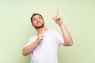 Yeşil arka plan üzerinde yakışıklı adam Dizin parmağı ile işaret büyük bir fikir