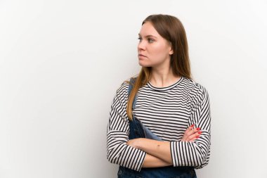 Beyaz duvar üzerinde dungarees genç kadın ayakta ve yan görünümlü