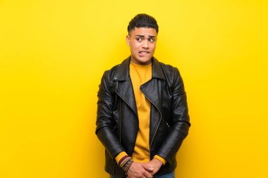 Karışık yüz ifadesi ile izole sarı arka plan üzerinde genç adam