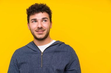 Izole sarı duvar üzerinde genç adam gülüyor ve yukarı bakıyor