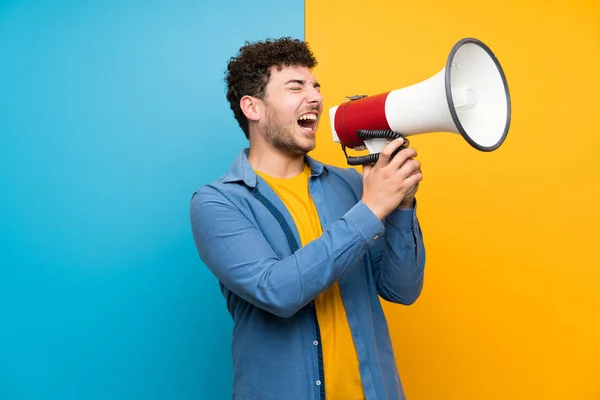 Man Met Krullend Haar Kleurrijke Muur Schreeuwen Door Een Megafone — Stockfoto