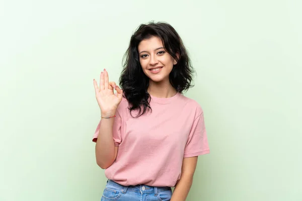 Молода Жінка Над Ізольованим Зеленим Тлом Показує Знак Пальцями — стокове фото