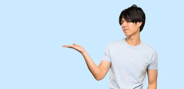 Asian Man Blue Shirt Holding Copyspace Doubts Isolated Blue Background — Stock Photo, Image