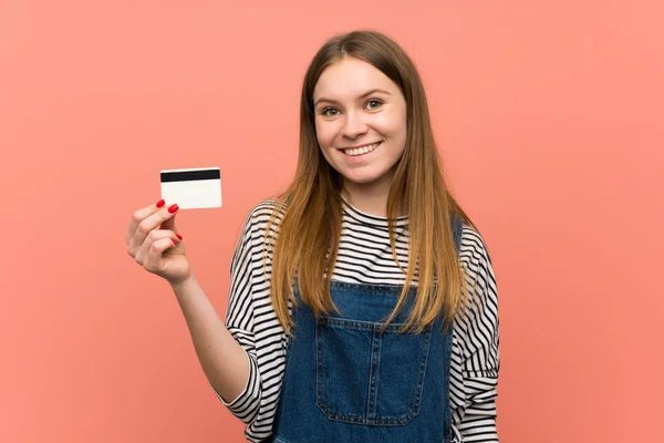 Mujer Joven Con Overoles Sobre Pared Rosa Sosteniendo Una Tarjeta — Foto de Stock