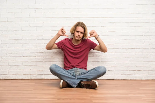 Blonde Man Zittend Vloer Tonen Duim Naar Beneden — Stockfoto