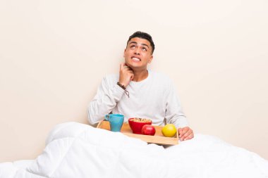 Yatakta kahvaltı olan genç adam bir fikir düşünerek