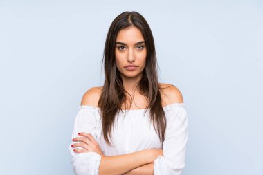 Izole mavi arka plan üzerinde genç kadın kollarını çapraz tutmak